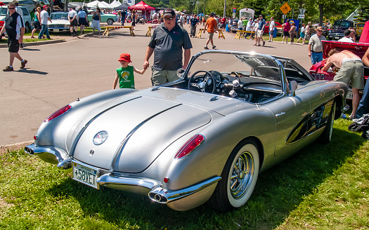 Moncton, New Brunswick, Canada - July 11, 2009 : 1958 Chevrolet Corvette at  Atlantic Nationals Automotive  Extravaganza Centennial Park. A man and young child walk by as the man takes a glance at the vintage Corvette.