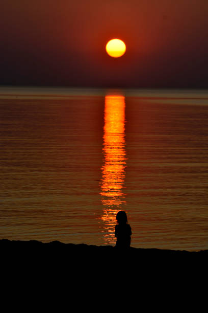 istock child and the setting sun over the sea 1208381573