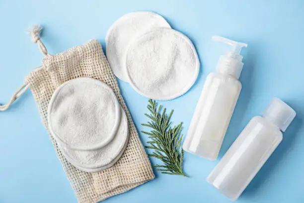 Cotton make-up removal pads and homemade DIY beauty products in reusable bottles.