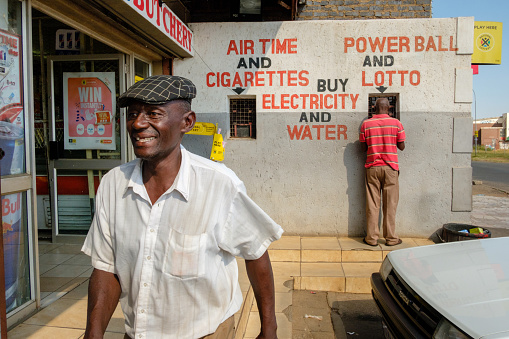 Johannesburg, South Africa - March 29, 2017: A local man smiles outside of shop selling lottery tickets and cigarettes along the streets of Johannesburg’s Soweto township, the largest township in South Africa.