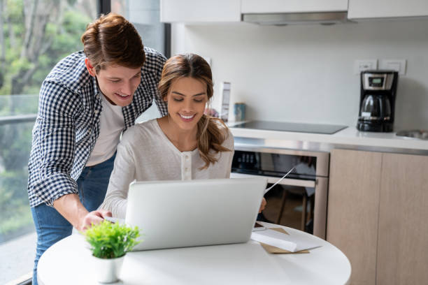 istock Happy young couple doing online banking using laptop to pay bills while at home 1208382195