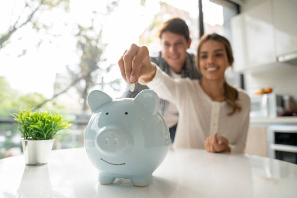 Focus on foreground of latin american young couple saving coins into piggy bank Focus on foreground of latin american young couple saving coins into piggy bank - Lifestyles piggy bank photos stock pictures, royalty-free photos & images