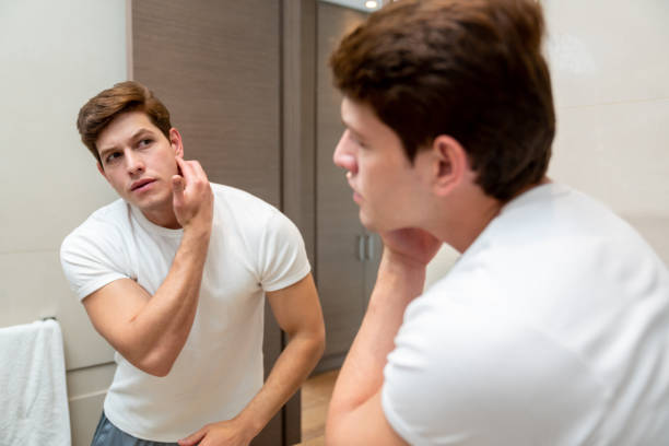 istock Handsome young man looking at an imperfection on his face during his morning routine 1208382237