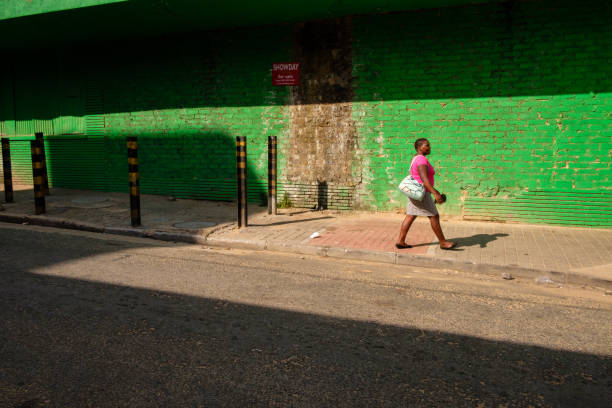 Johannesburg, South Africa - April 1, 2017: A local woman wearing pink walks by a green wall on the street in Johannesburg’s Maboneng district.