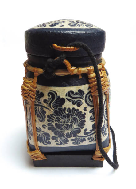 istock Thai wicker box with lid for storing rice seeds, handmade and painted blue on white background. Circular lacquered bamboo basket, woven on a square wooden base. View with closed lid. Traditional handmade craftsman. 1208386222