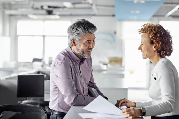 istock Smiling mature coworkers discussing at office 1208388952