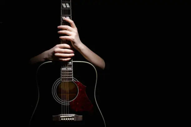 Young Woman Hugging With Her Hands Guitar, Isolated On Black