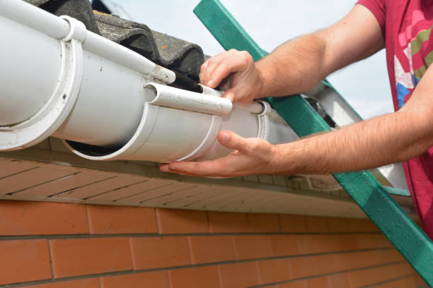 istock Gutter pipeline installation. Roofer contractor installing and repair rain gutter. Guttering repair with contractor hands. 1208389398