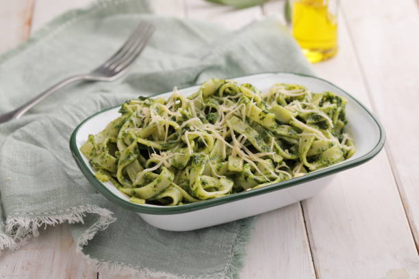 istock Fettuccine pasta with pesto sauce and cheese on a rustic table covered by an olive napkin 1208390593