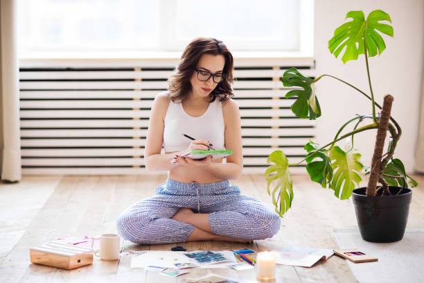 young brunette woman creating her feng shue wish map using scissors - fengshui imagens e fotografias de stock