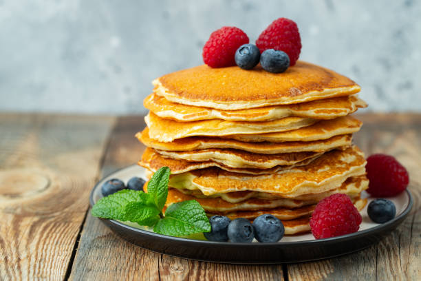 istock Close-up delicious pancakes, with fresh blueberries, raspberry's and honey on a light background 1208393956