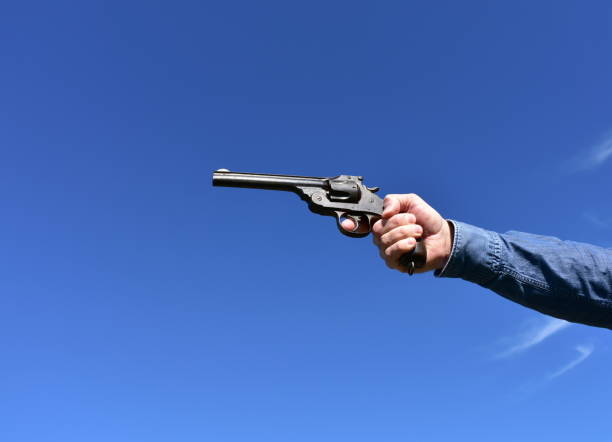istock Man holding a .44 or .45 caliber revolver outdoors with blue sky. 1208394415