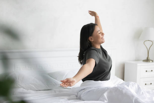 istock Overjoyed biracial woman wake up in bed stretching 1208397466