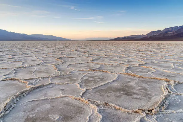 Salt flats in Badwater Basin in Death Valley national park , California during sunset with majestic mountains.