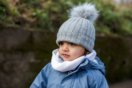 Young Mixed Race Boy dressed in warm winter clothes outdoors in the park.