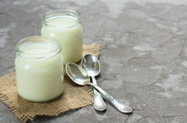 istock Two jars of natural yogurt and small spoons on a gray background.Copy space. 1208401889