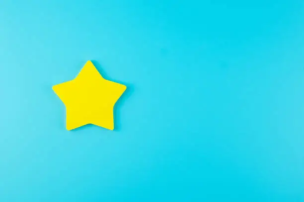 Photo of one star yellow paper note on blue background with copy space for text. Customer reviews, feedback, rating, ranking and service concept.