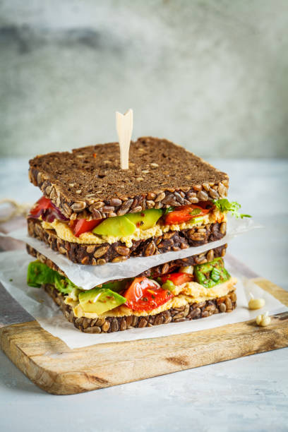 Vegan sandwiches with hummus, tomatoes, avocados and seedlings on whole grain bread. Vegan sandwiches with hummus, tomato, avocados and seedlings on whole grain bread. grain sprout stock pictures, royalty-free photos & images
