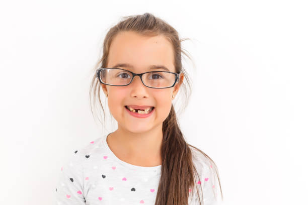 istock Little girl first tooth missing on a white background 1208406490