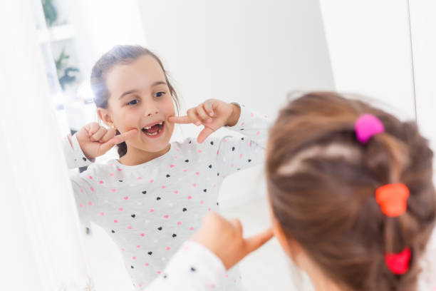 istock little girl smiling mirror teeth 1208408489