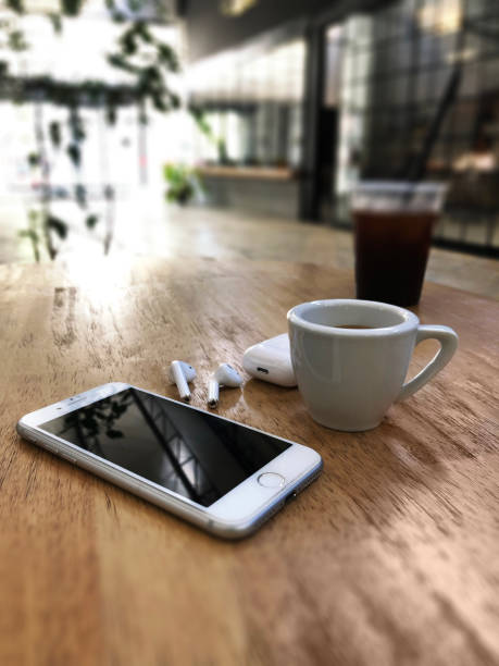 White colored Apple brand Iphone 8 Phone and Airpods 2 on a wooden table with charging box and cup of espresso Izmir, Turkey - July  11, 2019: White colored Apple brand Iphone 8 Phone and Airpods 2 on a wooden table with charging box and cup of espresso on a wooden table. iphone 8 stock pictures, royalty-free photos & images