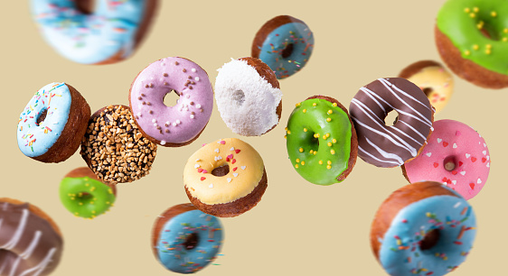 Colorful Donuts flying on yellow background. Sweet food background.