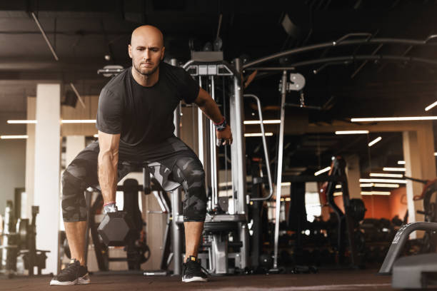 istock Caucasian athletic man bodybuilder doing exercises with dumbbell in gym 1208410374