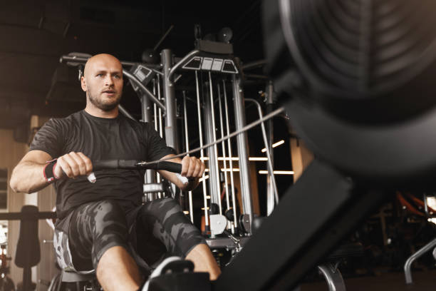 istock gym young adult man using rowing machine in the gym for training 1208410421