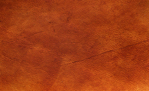 istock Orange nut brown vegetable tanned leather closeup full frame macro texture showing top grain and wear scratch marks 1208411496