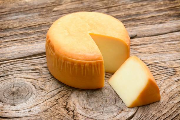 cheese wheel on wooden table - cheese wheel cheese cheddar wheel imagens e fotografias de stock