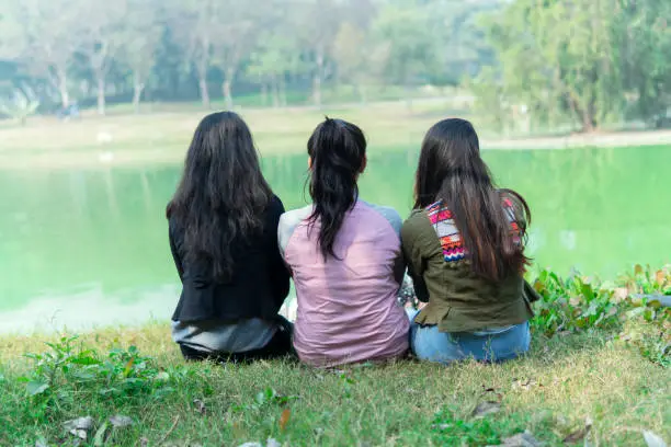 Photo of Young girls are sitting near the lake and enjoying the nature