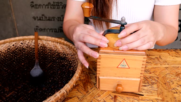 Barista grinding coffee by hand on a vintage coffee grinder