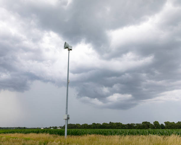 alerta meteorológico severo e sirene de alerta de tornado ao longo da estrada rural com nuvens de tempestade escura e chuva ao fundo - tornado storm disaster storm cloud - fotografias e filmes do acervo