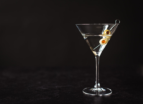 Close up of a classic martini cocktail against a black background.