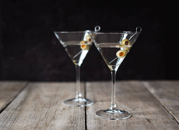 istock Two classic martini cocktails on wooden table with black background. 1208417082