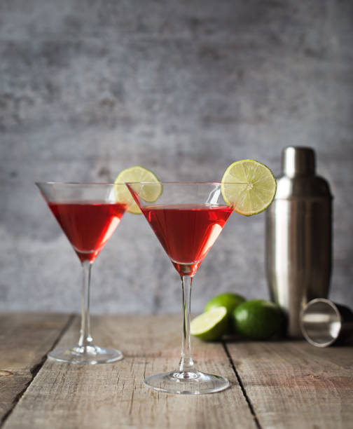 istock Cosmopolitan martini drinks, shaker and limes on wooden table. 1208417084