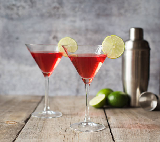 istock Cosmopolitan martini drinks, shaker and limes on wooden table. 1208417106