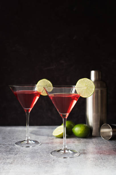 istock Two cosmopolitan martinis, shaker and limes on a gray counter. 1208417129