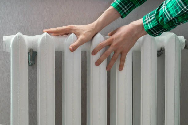 istock frozen hands touch a heating battery at home during winter season 1208417236