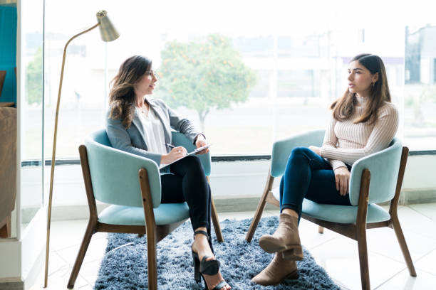 woman talking to therapist at office during treatment - psychiatrists couch imagens e fotografias de stock