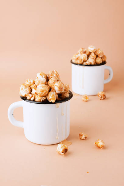 Caramel popcorn in vintage white metal cups on a brown background stock photo