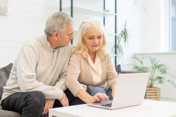 istock Smiling beautiful elderly lady typing on laptop at home 1208422558