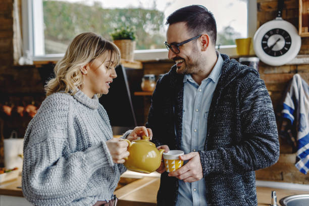 istock Happy couple talking while having a cup of tea in the kitchen. 1208423743