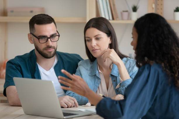 istock Mixed race financial advisor showing presentation on laptop to clients. 1208424272