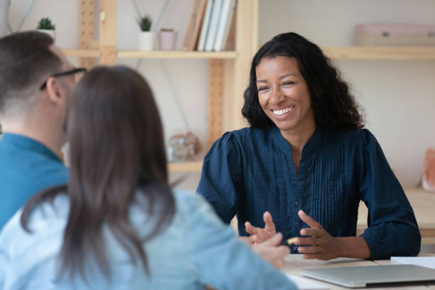 istock Smiling professional african american financial advisor talking to clients. 1208424282