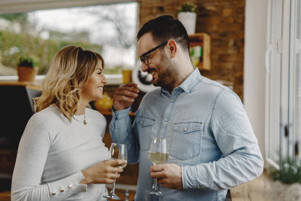 istock Happy couple communicating while drinking wine in the kitchen. 1208429467