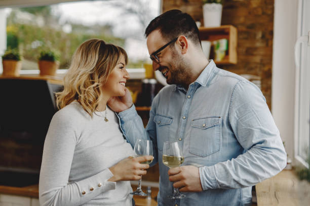 istock Loving couple drinking wine and talking in the kitchen. 1208430131