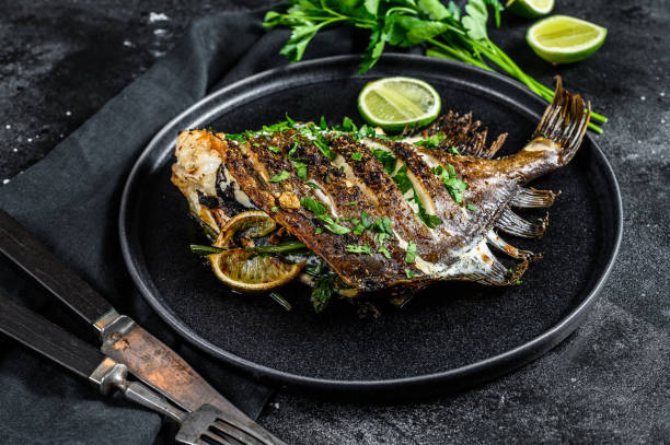 grilled john dory fish with lime and parsley in a pan. black background. top view - dory imagens e fotografias de stock