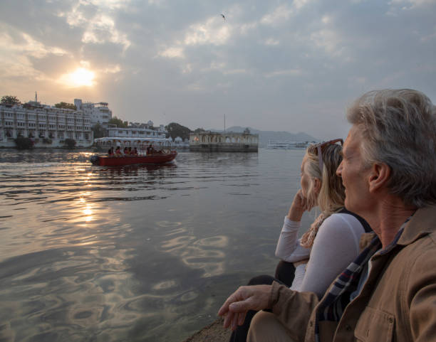 Mature couple explores a ghat at sunrise They look across water. Lake Pichola, Udaipur lake palace stock pictures, royalty-free photos & images