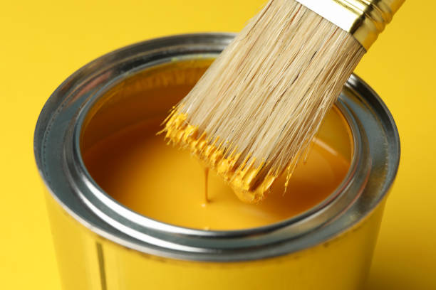 istock Paint can and brush on yellow background, close up 1208436344